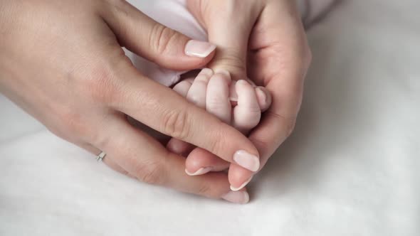 Close Up of Mothers Tender Palms Hold Little Cute Hand of Newborn Baby alt