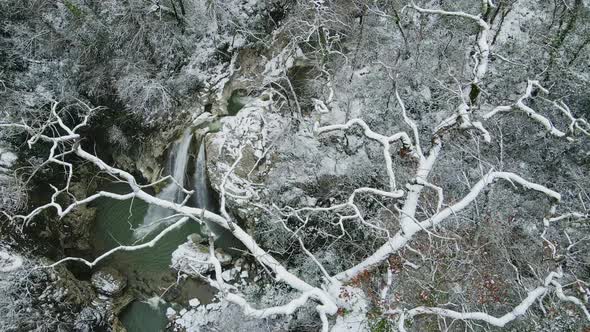 Waterfall Flowing Down From Rocks Shot Through the Branches of a Tree in Winter alt