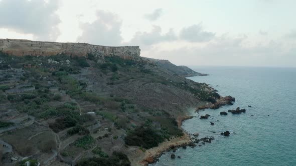 Coastline of Malta Island at Sunset with Cliff and Ocean Waves, Aerial Drone Perspective Forward alt