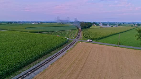 Aerial View of a Steam Train Approaching Flying Ahead Traveling Thru Farmlands and Corn Fields alt