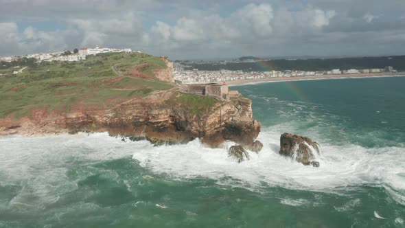 Flying over a wild sea crashing on rocks towards Fort of São Miguel Arcanjo (St. Michael the Archang alt