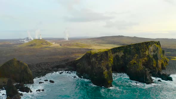 Rocks Stand on the Shoreline with Crashing Waves at Reykjanesviti, Iceland Aerial Pullback alt