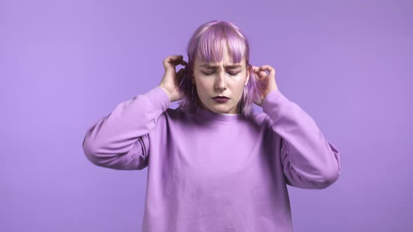 Angry Offended Woman with Dyed Purple Hair Keeping Arms Crossed and Staring at Camera with Sceptical alt