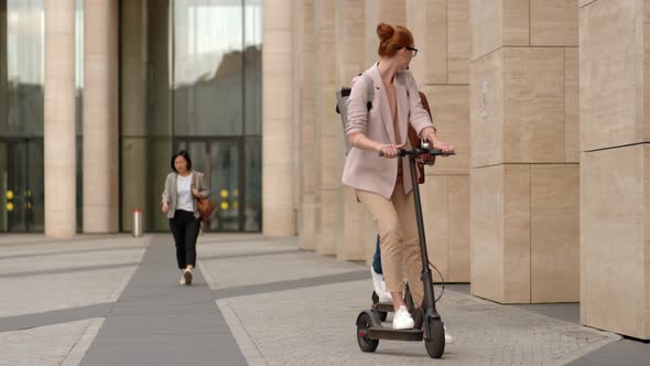 Young Diverse Man and Woman Riding E-scooters alt