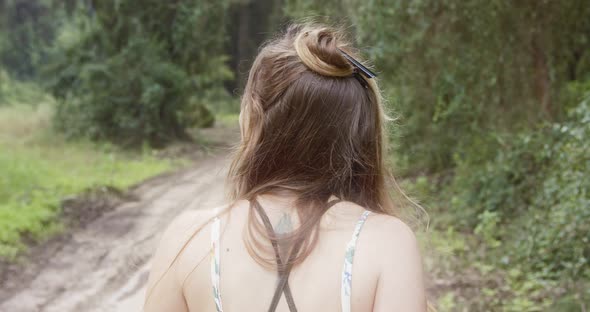 Young beautiful woman with a white dress walking in a green forest alt