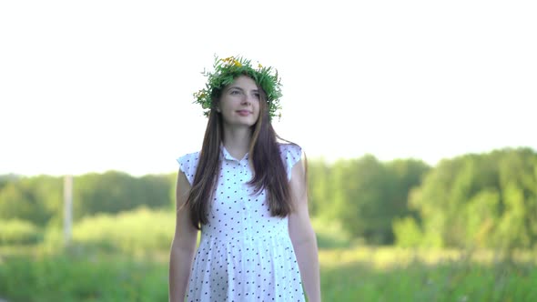 Pregnant Woman with a Wreath on Her Head Walks Outdoors