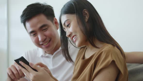 Close up Asian couples using smartphones browsing social media communication.