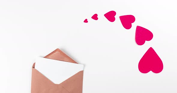 craft paper envelope and red flying hearts on white background
