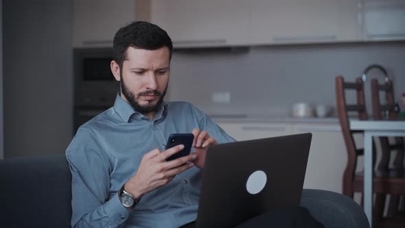 Man Using Smartphone and Laptop at Home alt