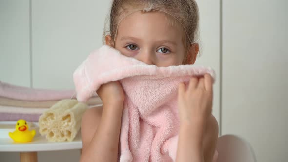Little Girl Wipes Wet Face with Terry Towel