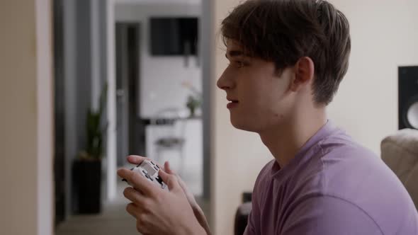 Beautiful Excited Young Gamer Man Sitting on a Couch Playing and Winning in Video Games on a Console alt