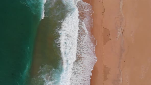 Aerial Top Down View of Beautiful Sandy Beach, Green Water Ocean and Waves Crashing on Sea Shore alt