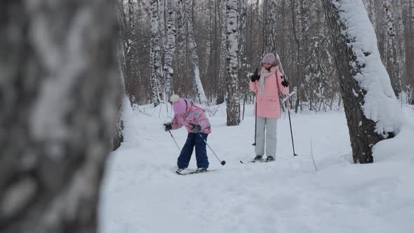 Child Ski Running with Mother in Winter Forest alt