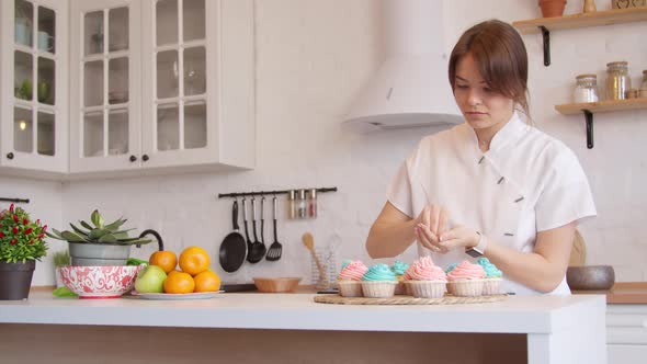 Woman Decorating Cupcakes in Kitchen