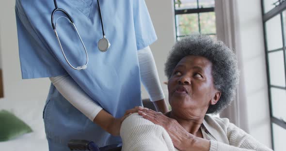 Caring african american female doctor helping senior african american female alt