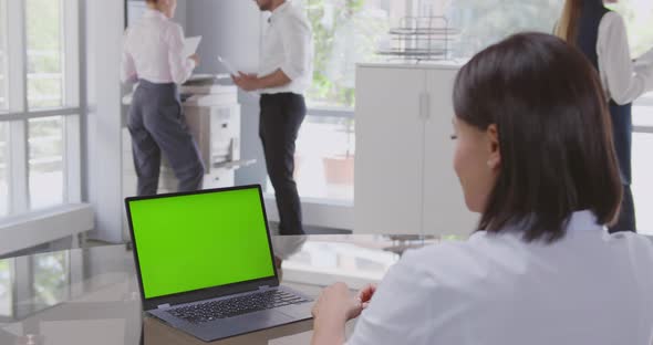 View Over Shoulder of African Businesswoman Sitting at Desk Looking at Laptop Green Screen alt