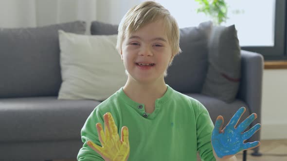 Happy Boy with Down Syndrome with Yellow and Blue Paint on Hands