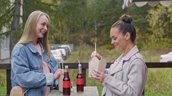 Two girls eating fast food outside