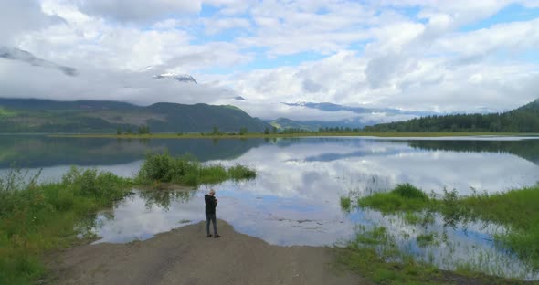 Aerial view of mature woman standing near a lake alt