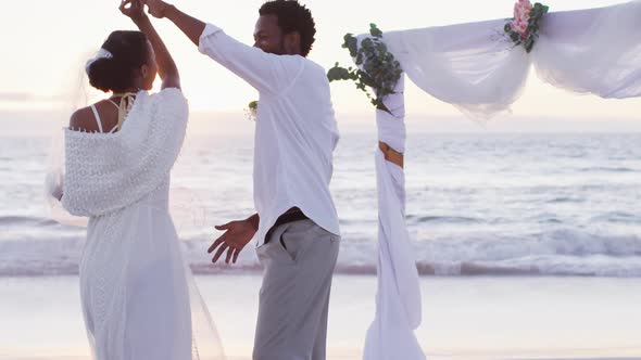 African american couple in love getting married, smiling and dancing on the beach at sunset alt