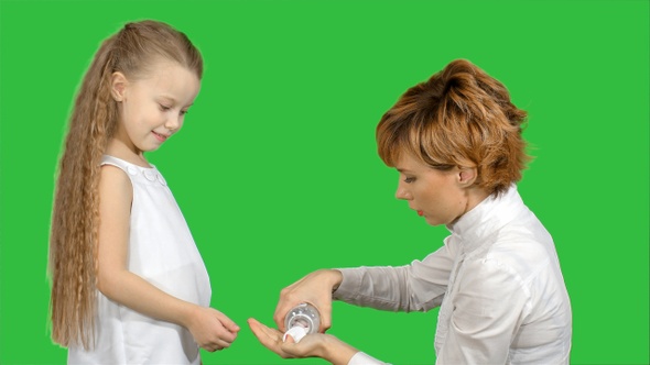 Mother giving her daughter medicine on a Green Screen, Chroma Key
