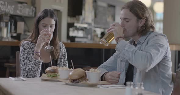 Man and woman enjoying drink and eating french fries in pub