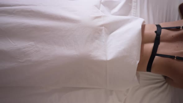 White Sheet Moving Aside with Slim Gorgeous Young Woman in Lingerie Lying in Comfortable Bed alt