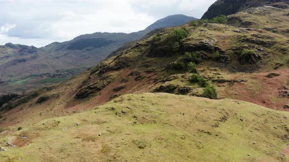 Aerial View Over Hills Towards Mountains