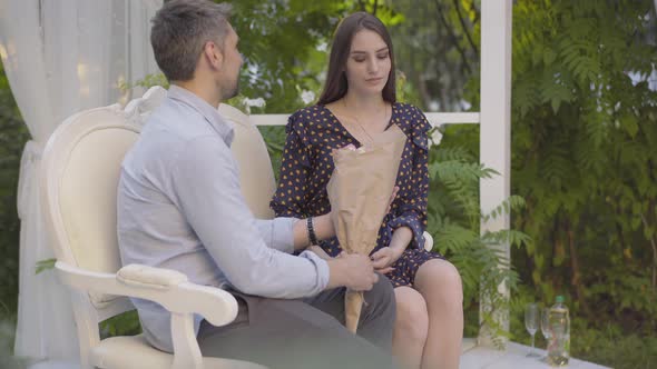 Loving Caucasian Man Giving Bouquet of Flowers To Happy Brunette Woman. Portrait of Beautiful Happy alt