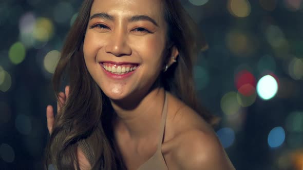 4K Portrait of Asian woman standing by the window at skyscraper at night. alt