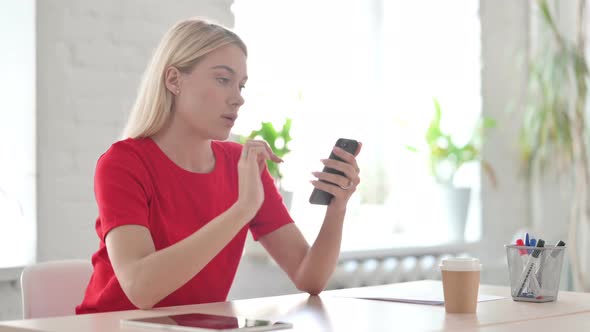 Upset Young Blonde Woman Reacting to Loss on Smartphone alt
