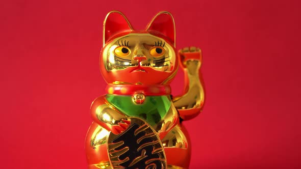 Sitting Maneki-neko cat waving with paw alt