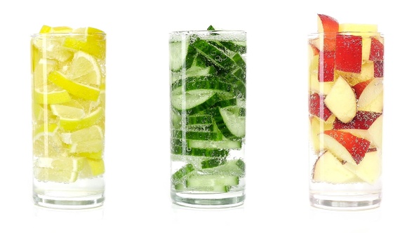 A refreshing vitamin drink made from lemon, cucumber and apple rotate on white isolated background.