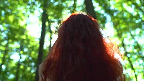 Girl playing with her long red hair alt