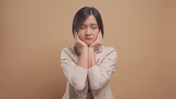 Asian business woman feel confused standing and looking at camera isolated over beige background.