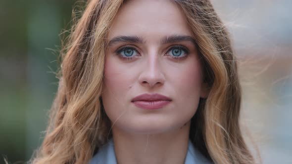 Extreme Closeup Female Serious Face with Natural Makeup Blue Eyes Looking at Camera Posing Outdoors alt