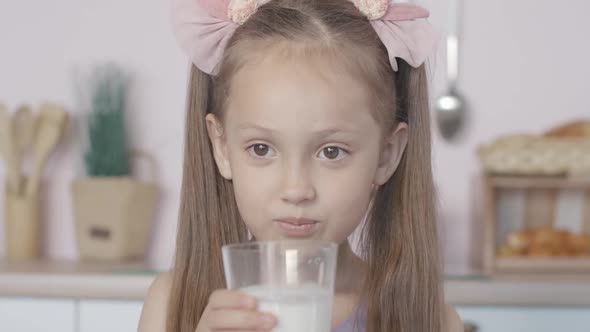 Close-up Face of Cute Little Girl Drinking Milk and Smiling. Portrait of Satisfied Caucasian alt
