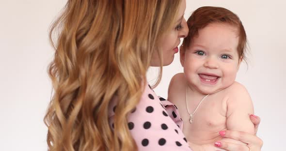 Mother Hugging and Kissing Little Child on White Background