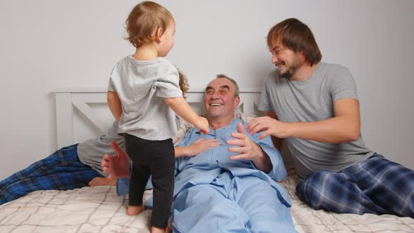 Aged Male Patient Embracing Kids and Talking While Lying on Bed at Home alt