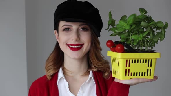 Woman in hat and red shirt with yellow basket full of vegetables