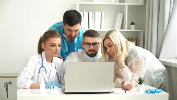 Team of Doctors Work at Laptop in Clinic