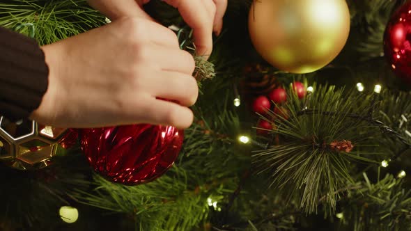 Close Up of Female Decorating Christmas Tree with Baubles