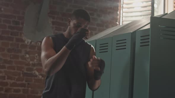 Male Boxer with Wrapped Hands Throwing Punches in Air alt