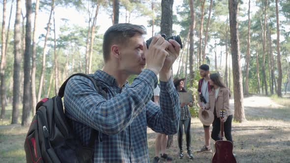 Portrait of Happy Absorbed Caucasian Man Making Photos of Nature in Sunny Summer Forest with Group alt