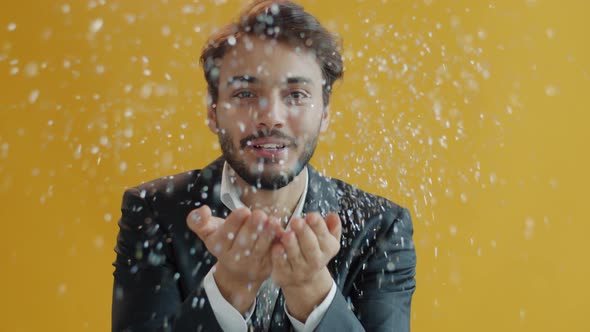 Portrait of Carefree Arab Guy Blowing Silver Confetti at Camera and Dancing alt