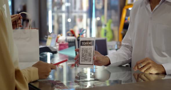 Young woman paying by scanning QR Code with smartphone alt