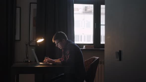 Freelancer Works at Home in a Room with Lamp