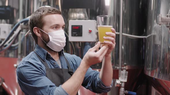 Brewery Worker In Mask With Glass Of Freshly Made Beer alt