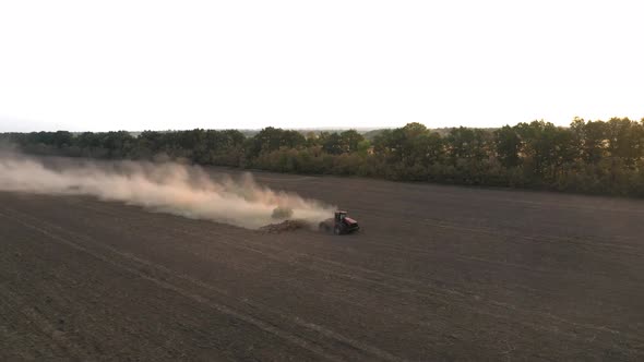 The Tractor Cultivates the Land in the Field and Applies Fertilizer To the Soil - Drone Orbit Shot alt