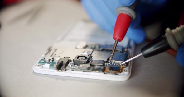 Repairman in Electronics Repair Service By Means of the Tester Checks Serviceability of the Device alt